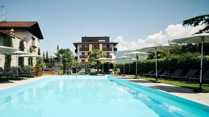 Traminerhof | good life. cool ride. © Manuel Ferrigato Outdoor swimming pool with loungers and umbrellas in front of a hotel building