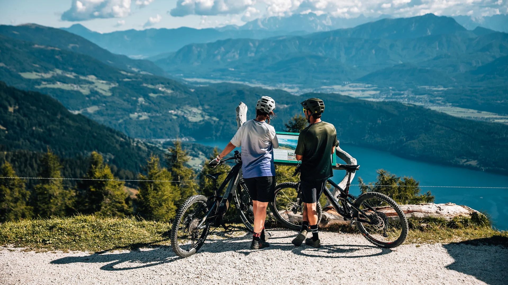 Mountain Bike Holidays © Jens Scheibe Zwei Radfahrer lesen eine Infotafel mit Berg- und Seeblick