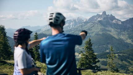 Flachau © Tobias Köhler Two cyclists looking at mountain panorama in the Alps on a sunny day