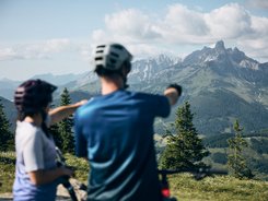Flachau © Tobias Köhler Two cyclists looking at mountain panorama in the Alps on a sunny day