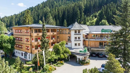 Hotel GUT Trattlerhof und Chalets © Gert Perauer Hotel Trattlerhof umgeben von Bäumen und Bergen im Sommer