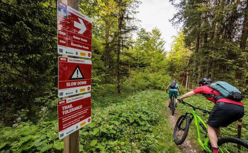 Mountain bike holiday in the Salzkammergut © Bikeboard.at - Erwin Haiden Two mountain bikers on forest trail next to signs with warnings and directions