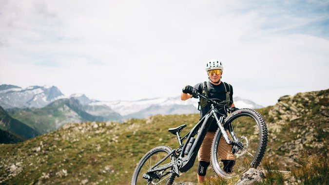 Mountain Bike Holidays © Martina Wunderle Mountainbiker mit Helm steht auf Felsen in bergiger Landschaft