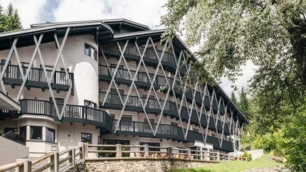 Hotel Arpuria | Hidden Luxury Mountain Home © Brandnamic Modernes mehrstöckiges Gebäude mit Balkonen und Holzgitterstruktur in grüner Landschaft