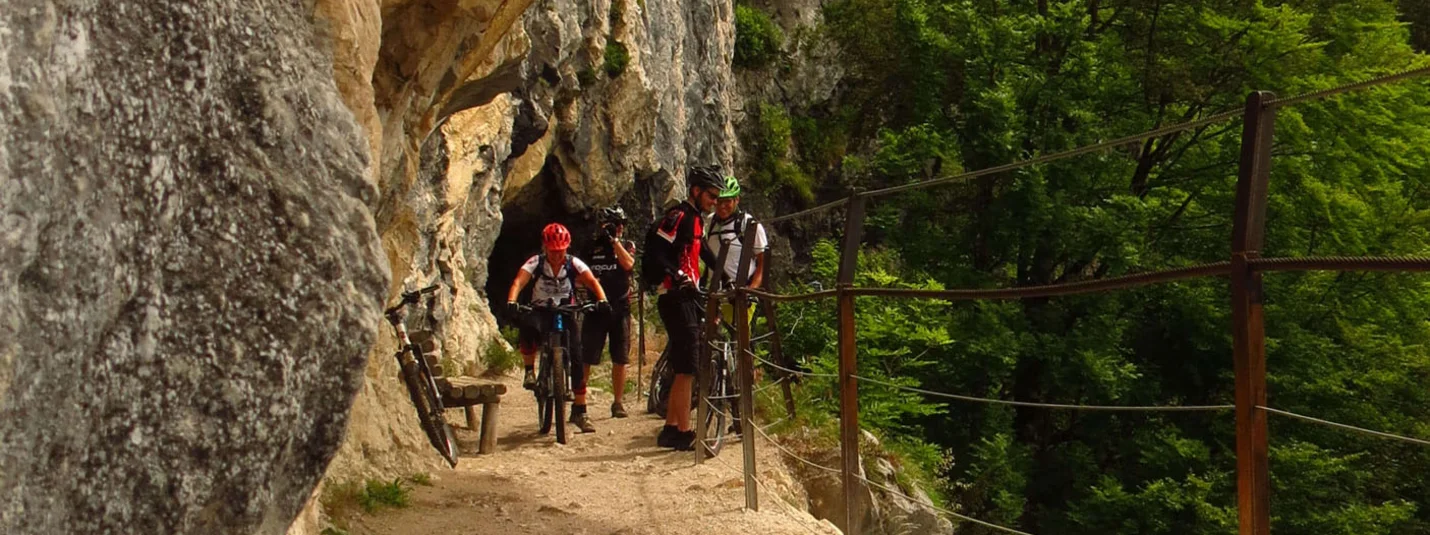 Nature Pleasure Tour © Bernhard Weissenhorn Cyclists on narrow rocky path with safety cable and forest in the background