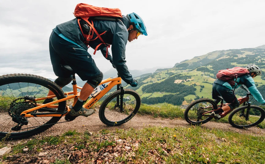 Lisi Osl Trail © Patrick Wasshuber Two mountain bikers riding on a trail with green hills in the background