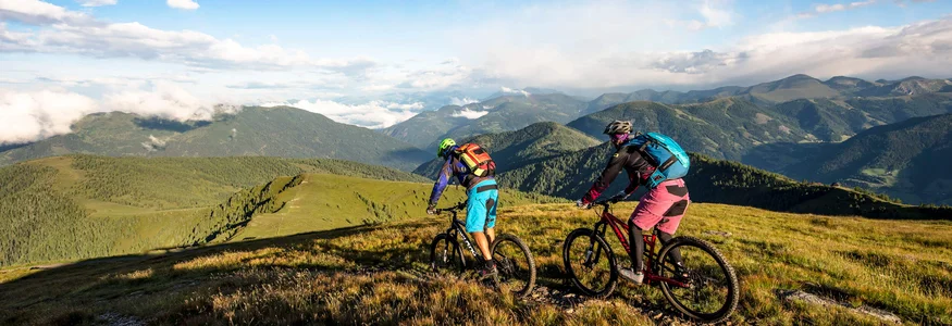 Alpe Adria World War Transalp © Franz Gerdl Two mountain bikers riding on a trail with a panoramic mountain view
