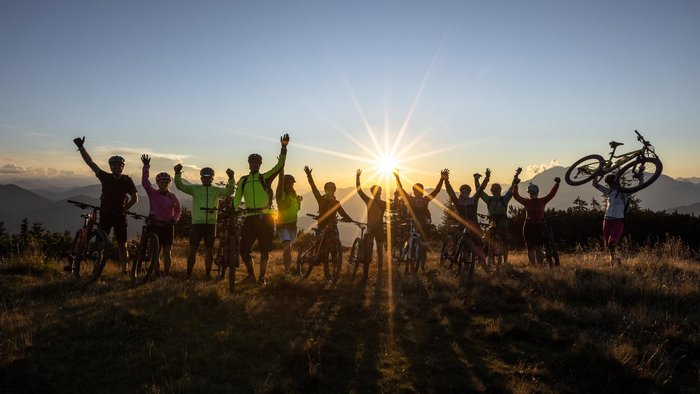 Biking as a group © Christian Huber Fotographie Group of cyclists celebrating at sunset on a mountain