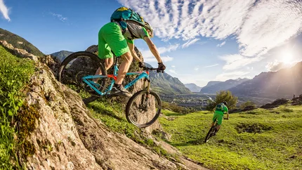 MONTIGGLER LAKES TOUR © WOM Medien Two mountain bikers descending a steep hill on a sunny day