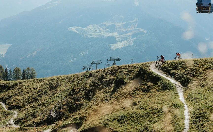 Mountain bike holiday in the Zillertal © Felix Saller Two mountain bikers on a trail with chairlift and forested mountains in background