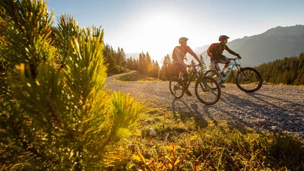Brandnertal Round Tour © Michael Marte Two mountain bikers cycling on a mountain trail at sunset