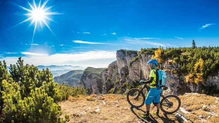 Monte Roen Trail © TVTramin - Antie Braito Mountain biker on a sunny mountain peak with cliffs and pine trees