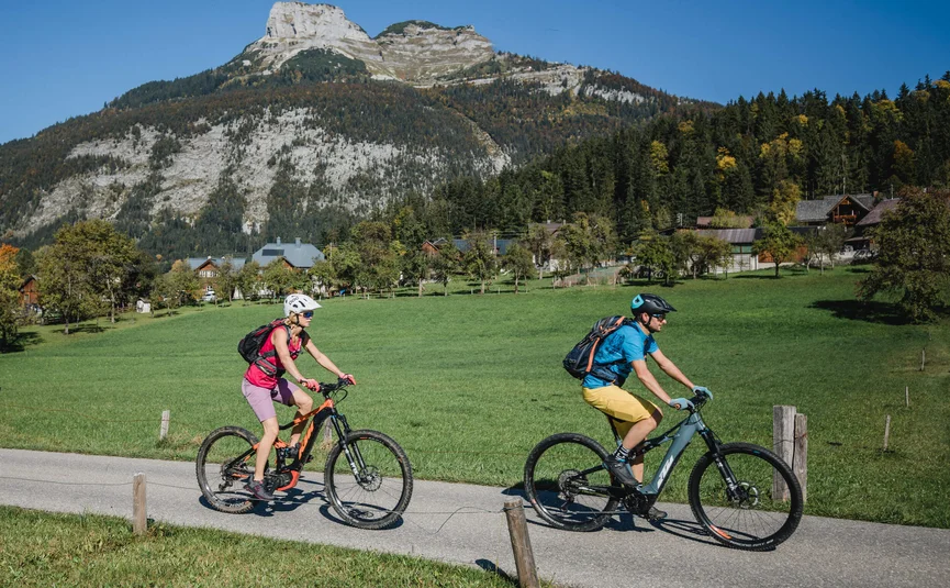 Mountain bike holidays in Styria © TVB Ausseerland Salzkammergut - Katrin Kerschbaumer Two cyclists riding on a country road with mountain backdrop on a sunny day