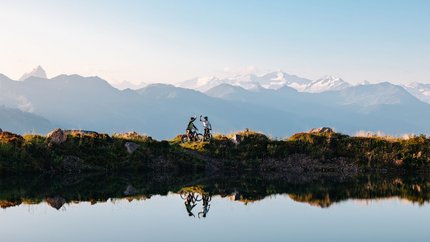 Kitzbühel Alps - Hohe Salve © Mathäus Gartner Two mountain bikers celebrating with mountain view by the lake