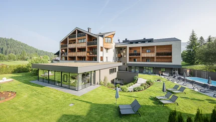 Hotel Laurin's © Harald Wisthaler Modernes Hotel mit Liegestühlen im Garten und Bergen im Hintergrund