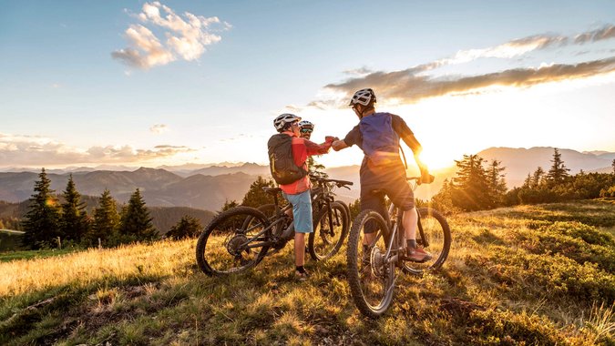 Mountain Bike Holidays © TVB Flachau - Ulrich Grill Zwei Mountainbiker grüßen sich bei Sonnenuntergang in den Bergen