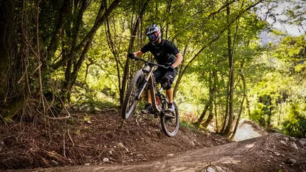 Airline © Bike Park Bovec Mountain biker jumping over a dirt trail jump in a forest