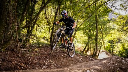 Airline © Bike Park Bovec Mountain biker jumping over a dirt trail jump in a forest