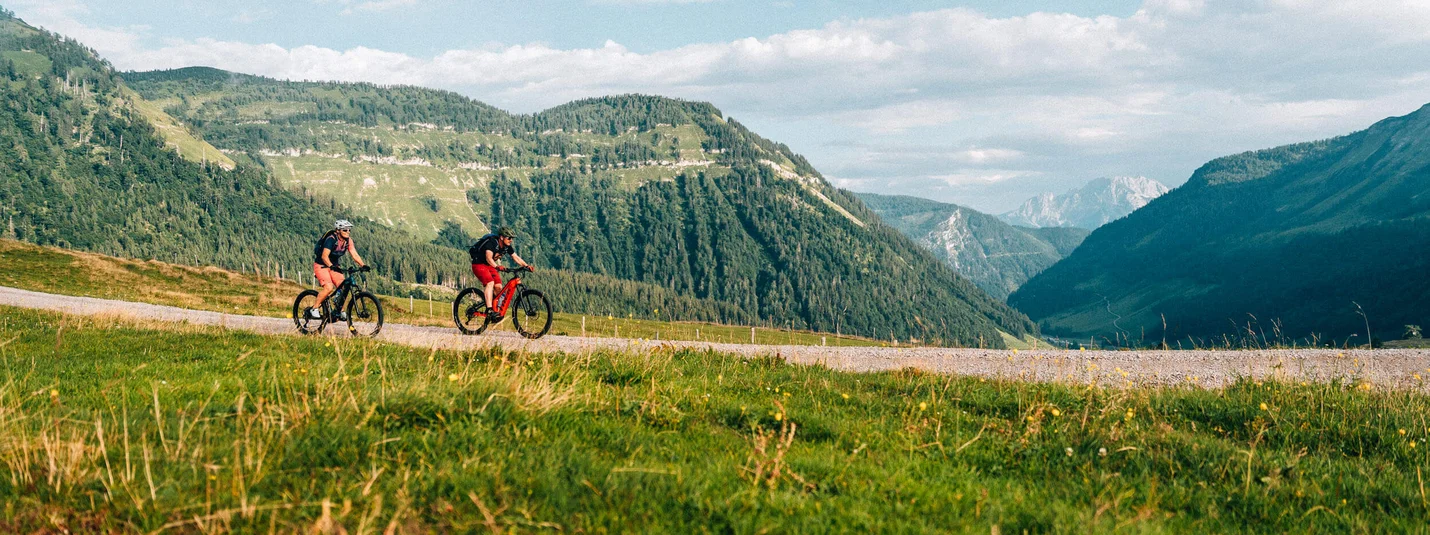 Sarstein ronde © Moritz Hübner Twee wielrenners op een bergpad met groene heuvels en bewolkte lucht