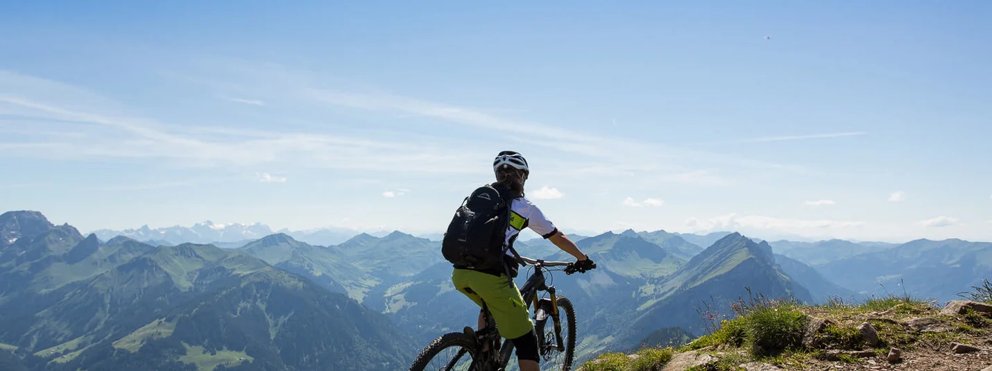 Au - Mellental Tour © Stephan Schatz Mountain biker on trail overlooking panoramic mountain view under clear sky