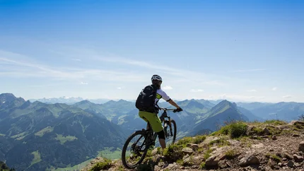 Au - Mellental Tour © Stephan Schatz Mountain biker on trail overlooking panoramic mountain view under clear sky