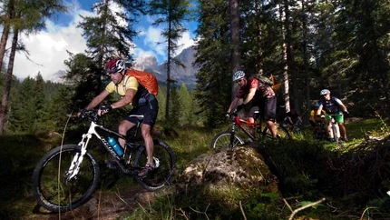 THE MONTE AGNELLO © Exploring GmbH Mountain bikers riding through forest trail with mountains in background
