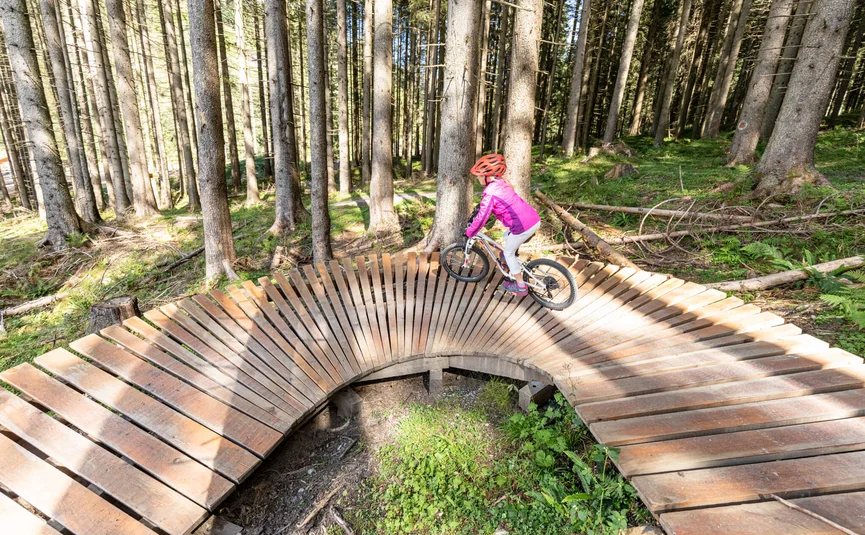 Mountain bike holiday in the Zillertal © Zillertal Arena Child riding bike on wooden BMX loop in forest