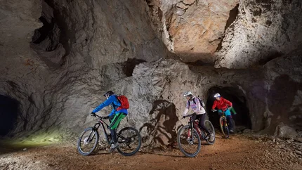 UNDERGROUND BIKING TOUR © Tomo Jesenicnik Three mountain bikers riding in a lit cave tunnel