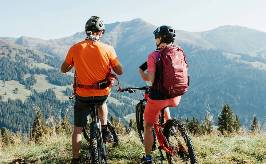 Mountain bike holiday in the Zillertal © Felix Saller Two cyclists wearing helmets overlooking mountains and forest from a hill
