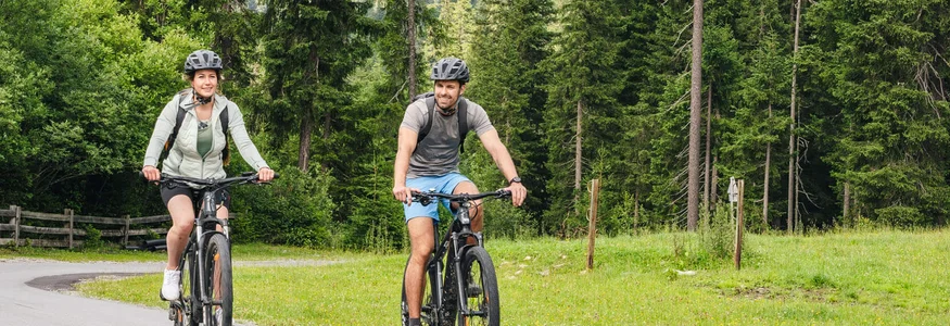 St. Anton am Arlberg © Brandnamic Man and woman riding mountain bikes on scenic forest mountain road