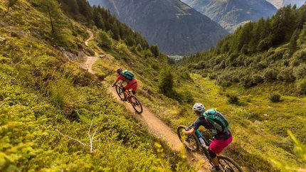 Ötztal © WOM Medien - Andreas Meyer Two mountain bikers riding on a mountain trail with mountains in view