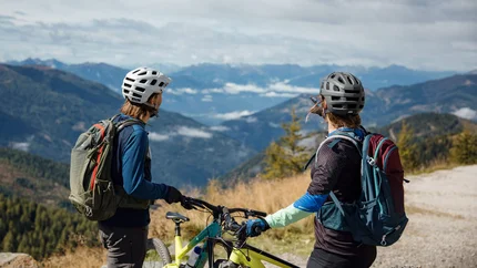 Natuurlijke oversteek bij de Törl - Millstätter Hütte rondreis vanuit Starfach © David Karg Twee fietsers met helmen en rugzakken op een berg met uitzicht op de vallei