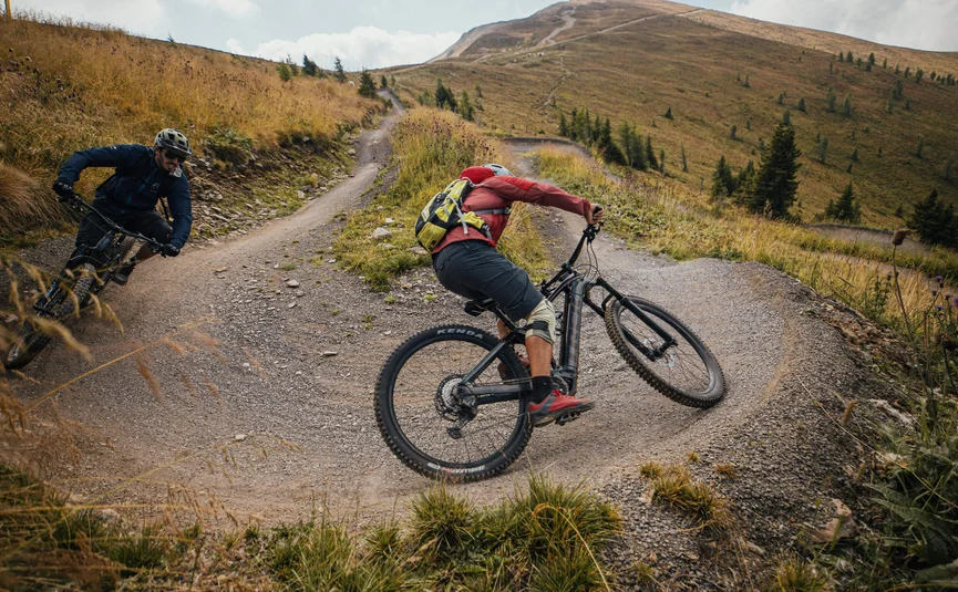 Mountain Bike holidays in the Weissensee region © David Karg Two mountain bikers riding on a winding mountain trail with grass and trees