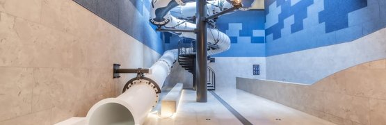 Familienurlaubswoche Innenrutsche in modern gestaltetem Raum mit blauen Wänden und Deckenbeleuchtung