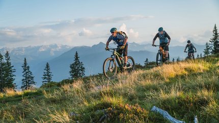 Rossbrand - Mandling Tour © Theresia Harml KG Three mountain bikers riding on a hilly trail in sunlight