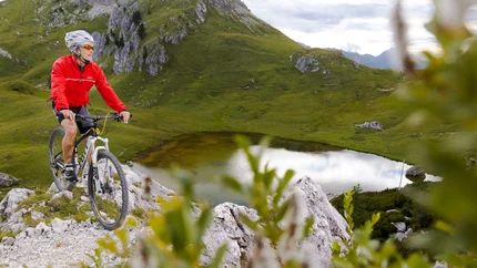 PEITLERKOFEL TOUR © Davide dal Mas Man mountain biking on rocky trail near lake and green hills