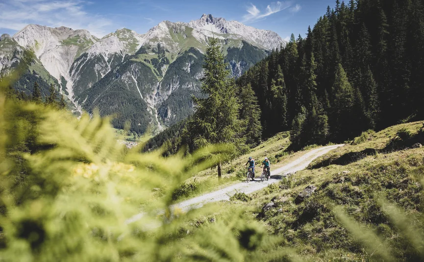 Mountain bike holidays in St. Anton am Arlberg © TVB St. Anton am Arlberg - Patrick Bätz Two cyclists on forest trail with mountain scenery in the background