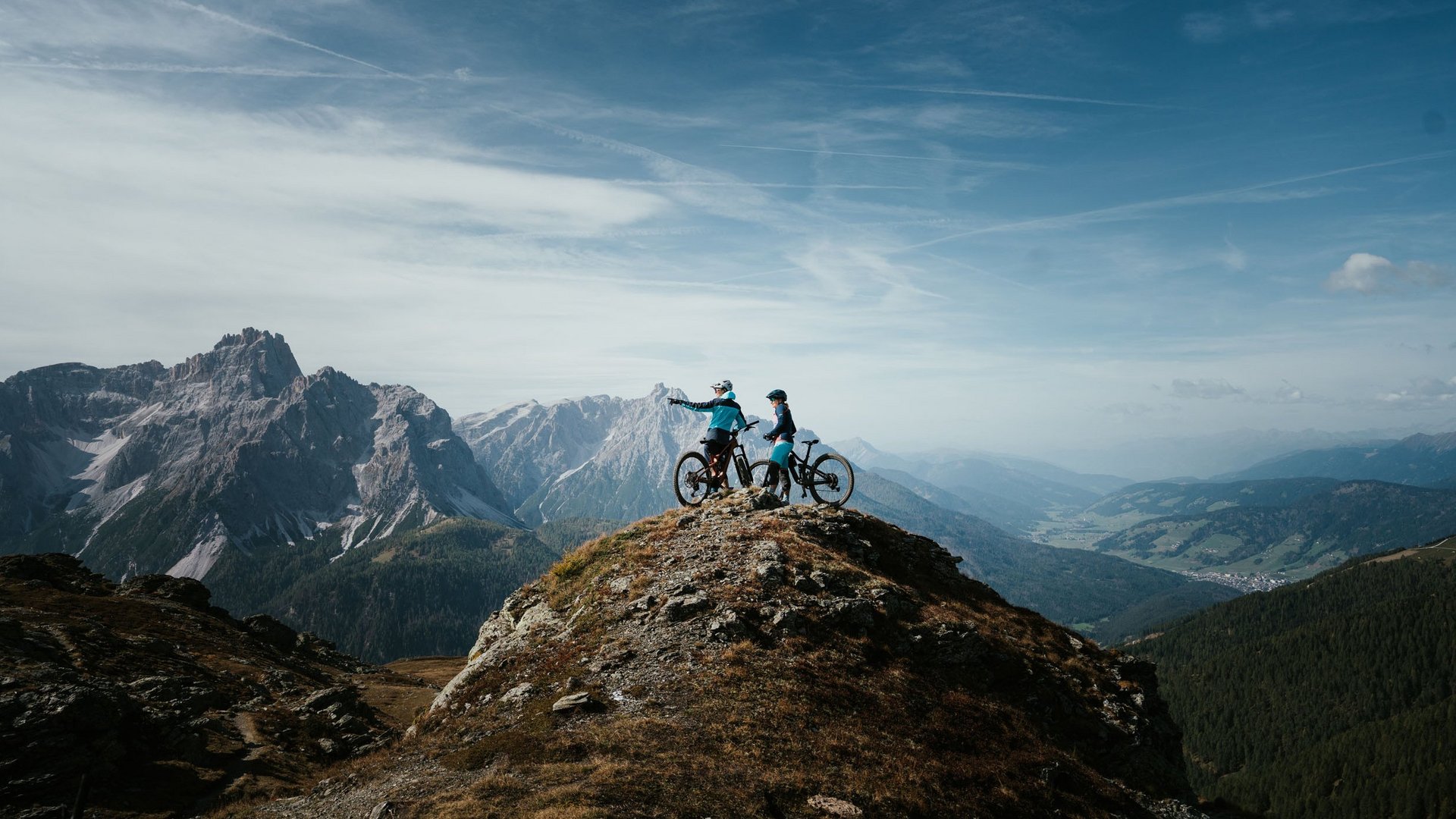 Mountain Bike Holidays © Desire Lines - Tobias Dörr Zwei Mountainbiker auf einem Berggipfel mit Ausblick auf Gebirge