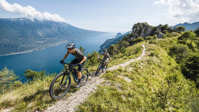 Mountain Bike Holidays © Marcus Greber Zwei Mountainbiker auf einem Bergpfad mit Seeblick