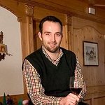 Mountain Bike Holidays © Hotel Digon St. Ulrich Mann sitzt auf Weinfass mit Weinflaschen und Glas in gemütlichem Raum