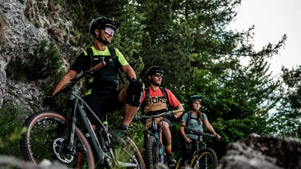 SENTIERO DELLA PACE © Andrea Acler Three mountain bikers with helmets resting on rocky trail in forest