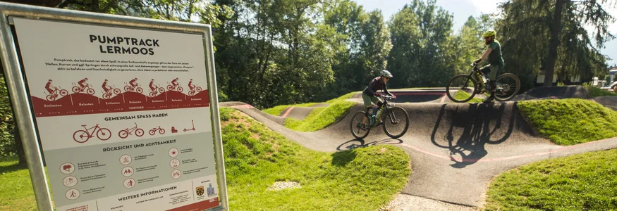 Tiroler Zugspitz Arena © David Karg Pumptrack in Lermoos with two cyclists and an information sign