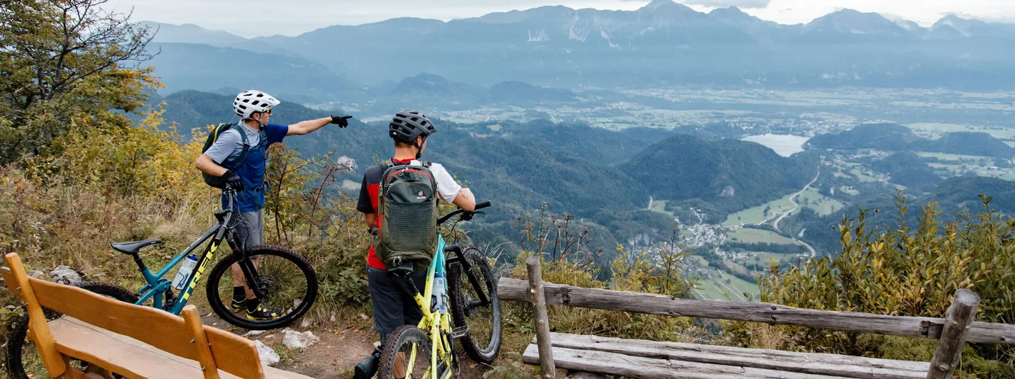 PLANINA KOFCE © David Karg Two cyclists on mountain overlooking valley and mountains