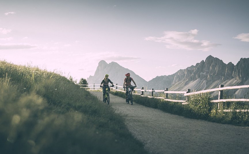 Mountain bike holiday in Brixen © Brixen Tourismus - Manuel Kottersteger Two cyclists riding on a mountain trail with mountains in the background