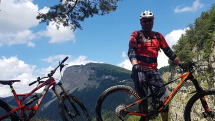 TOUR VAL GARDENA - VALLUNGA - S. GIACOMO © Hotel Digon St. Ulrich Mountain biker standing with two bikes on rocky mountain trail with cliff and sky