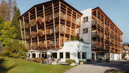 Hotel Melodia del Bosco © Alex Moling Hotel Melodia del Bosco mit Holzfassade und Blumen auf Balkonen im Grünen