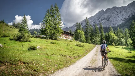Kupfnerberg – Finsingtal – Hochfügen Tour © Greenstorm Cyclist on mountain path with house, pine trees, and rocky mountains