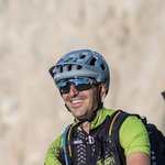 Mountain Bike Holidays © Harald Wisthaler Mann mit Mountainbike und Helm sitzt auf einer Wiese vor Bergen