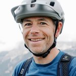 Mountain Bike Holidays © Szymon Bike Mann mit Fahrradhelm und Rucksack vor Bergpanorama