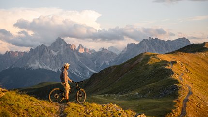 3 Peaks Dolomites © Elias Ochner - Stefan Schwabl Mountain biker on trail overlooking Dolomites at sunset